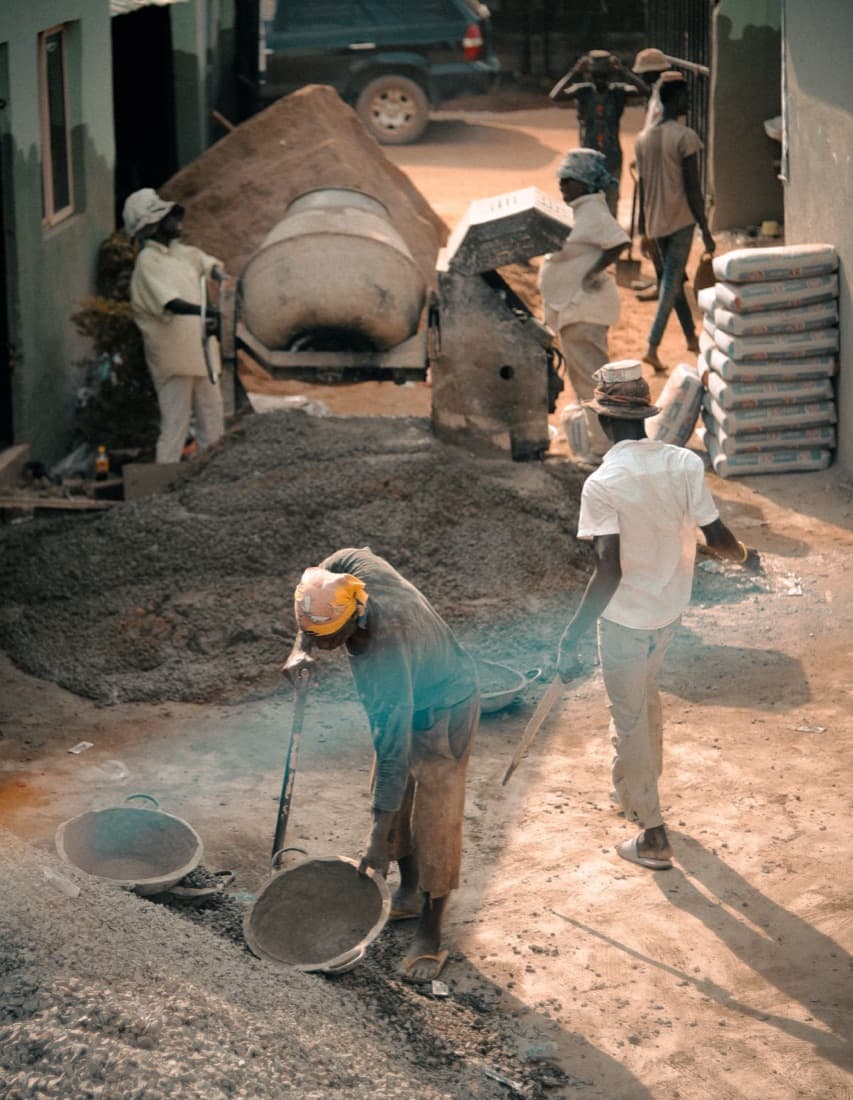 Chantier de construction avec bétonnière, sacs de ciment et maçons au travail